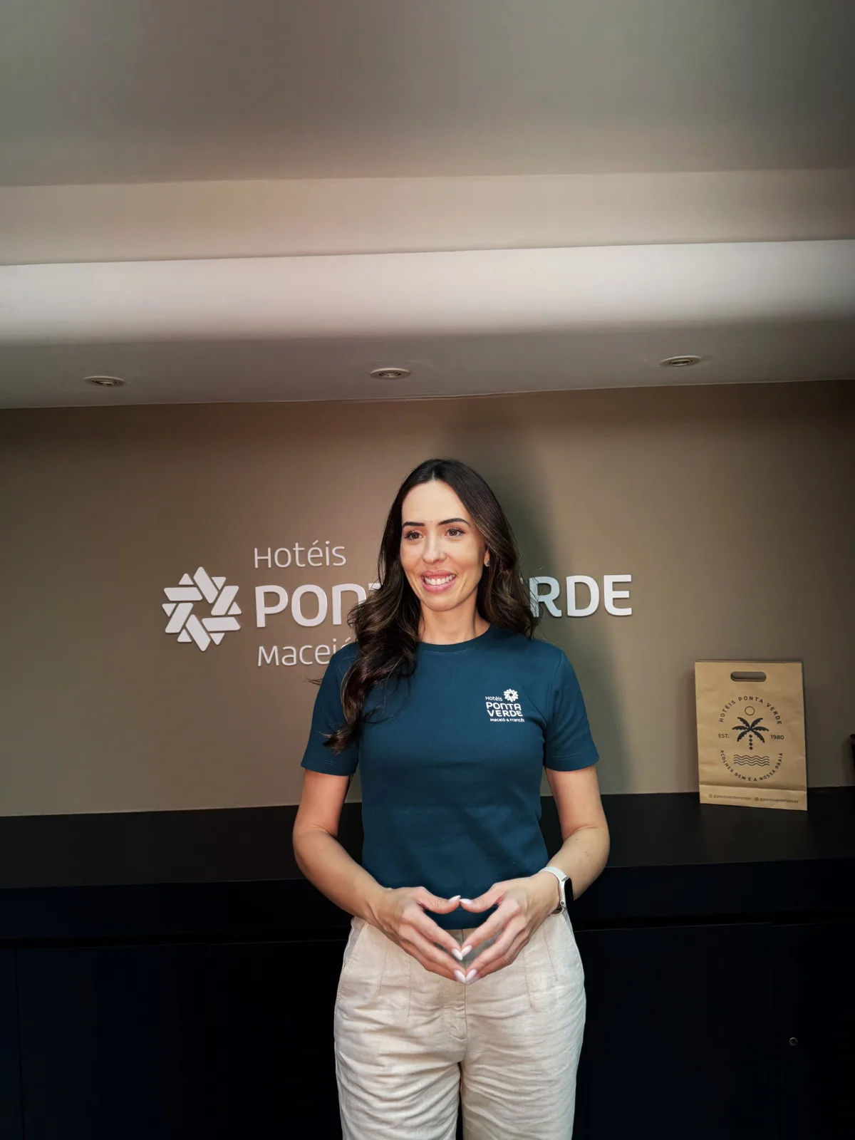 Ana Laura, dos Hotéis Ponta Verde, em frente à marca do hotel em Maceió